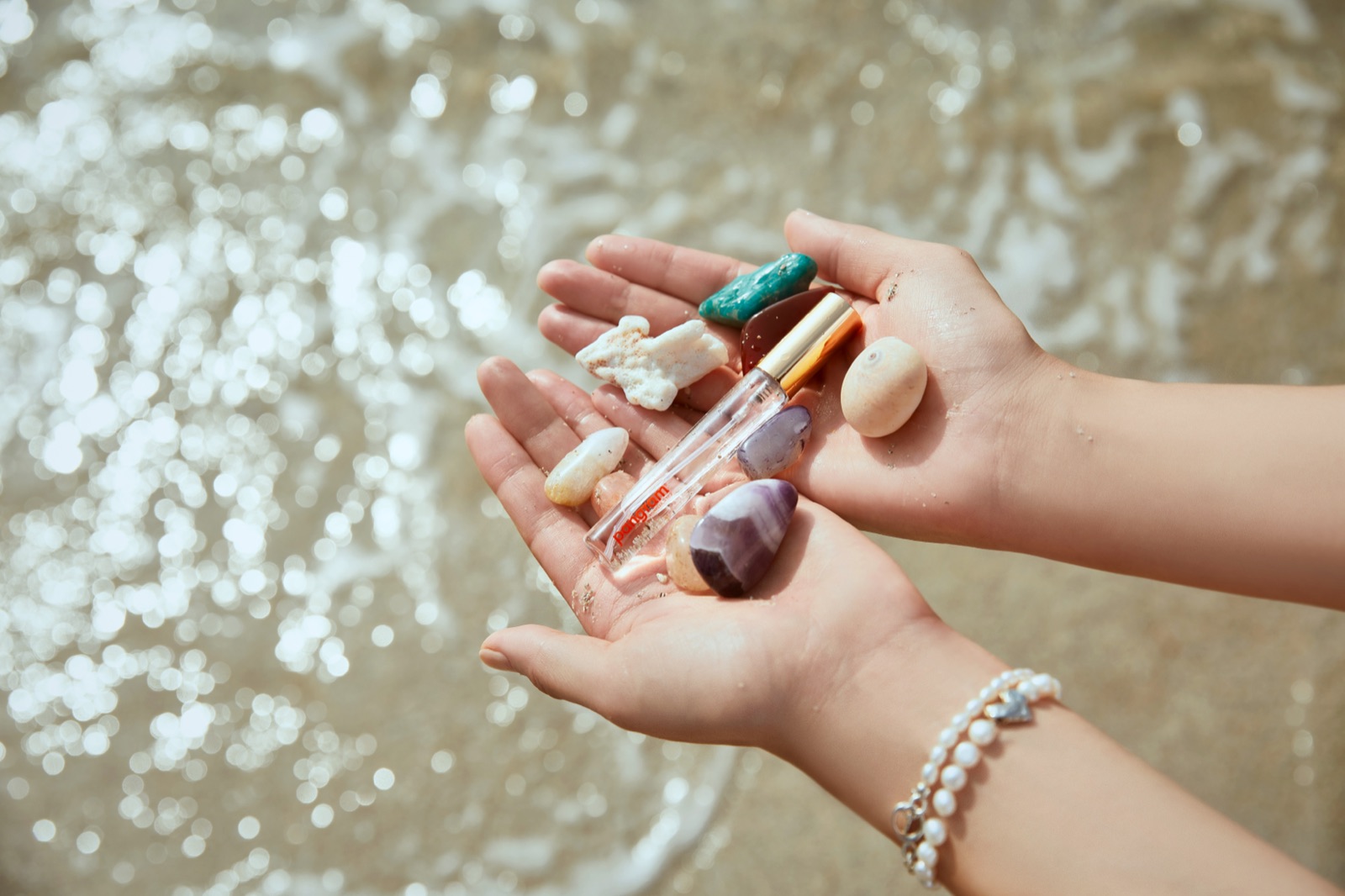 Pangram products and natural objects held in a hand above seawater